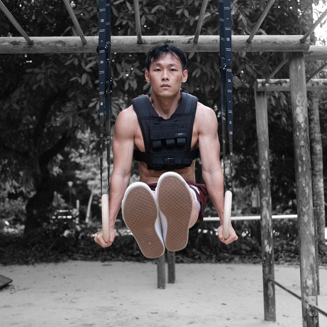 man wearing grav weighted vest doing l-sit on grav gymnastic rings